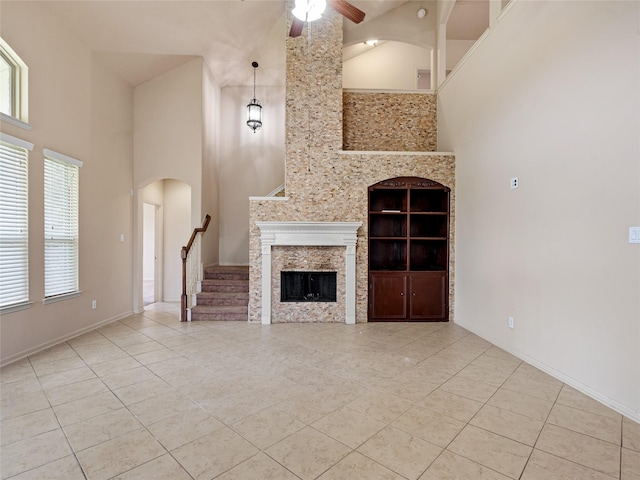 unfurnished living room with tile patterned floors, ceiling fan, a high ceiling, and stairway