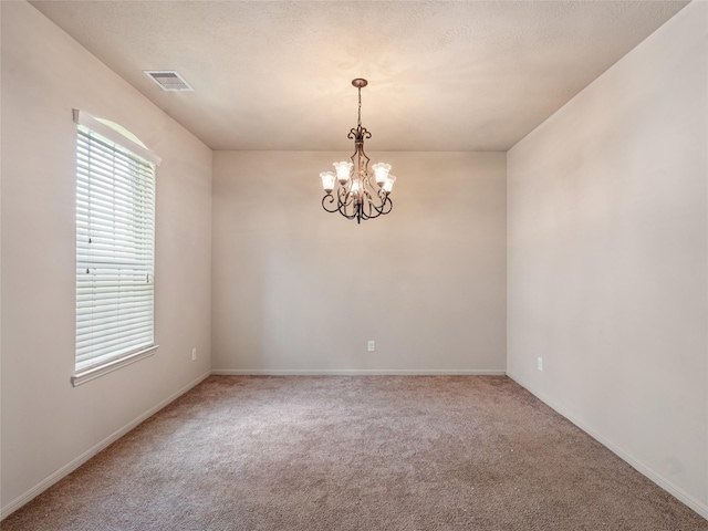 empty room with a notable chandelier, visible vents, baseboards, and carpet