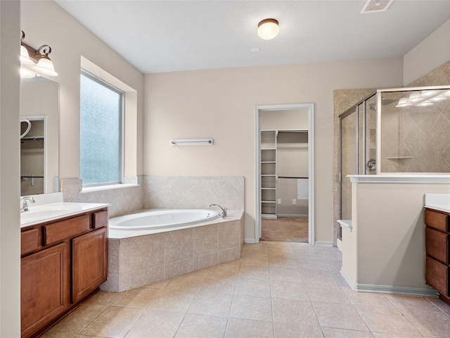 full bathroom with vanity, a stall shower, a bath, and a walk in closet