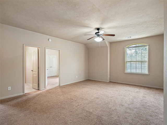 spare room featuring visible vents, light carpet, baseboards, ceiling fan, and a textured ceiling