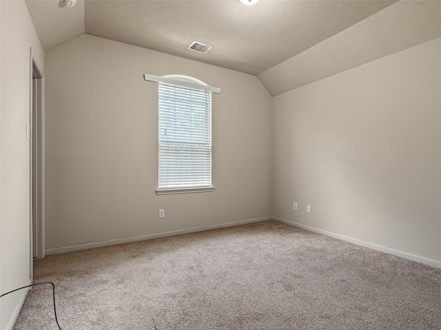 carpeted empty room with baseboards, vaulted ceiling, a textured ceiling, and visible vents