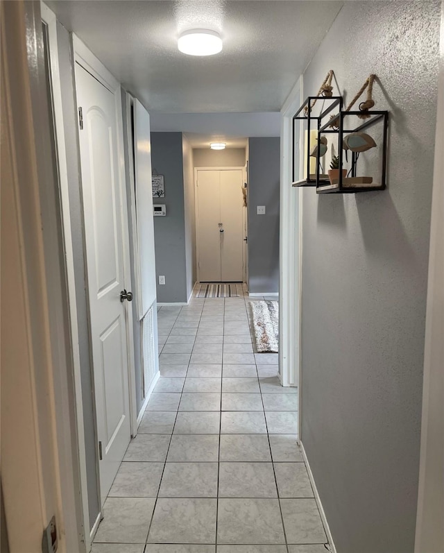 hall with light tile patterned floors and baseboards
