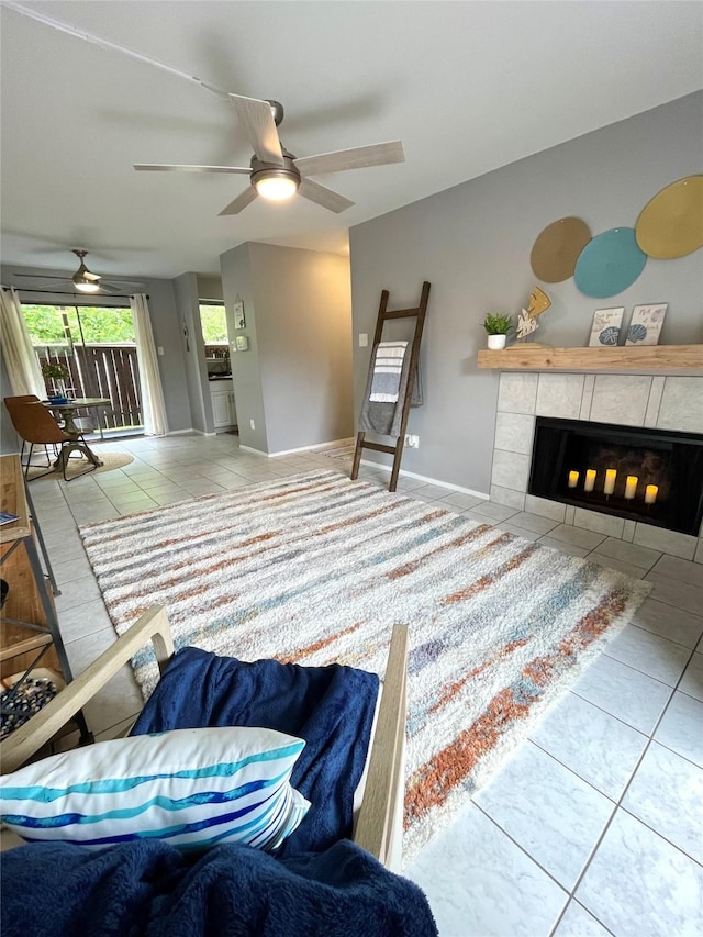 living area with baseboards, tile patterned flooring, a fireplace, and a ceiling fan