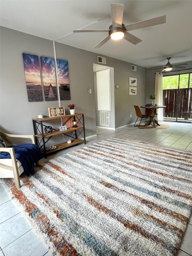tiled living area featuring visible vents, a ceiling fan, and baseboards