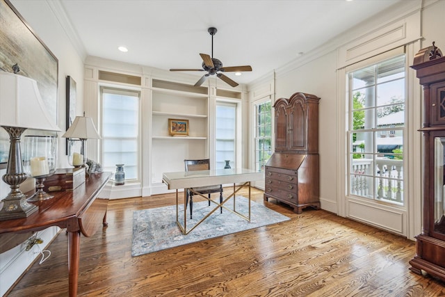 office space featuring a ceiling fan, crown molding, built in features, wood finished floors, and recessed lighting