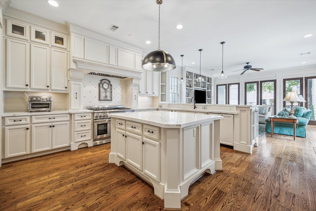 kitchen with a peninsula, high end stainless steel range, dishwashing machine, a center island, and dark wood finished floors