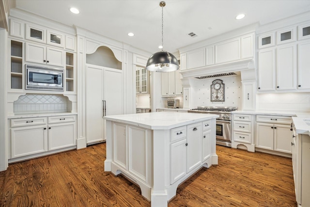 kitchen with appliances with stainless steel finishes, a kitchen island, white cabinetry, and visible vents