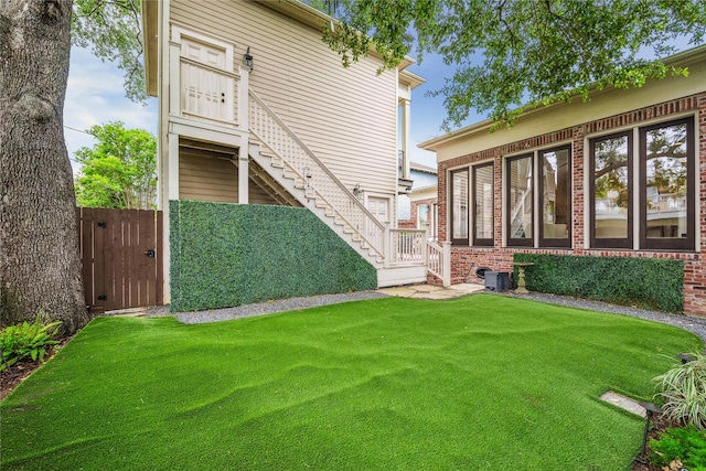 rear view of house featuring a lawn, a gate, stairs, and brick siding