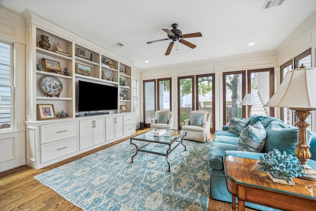 living room featuring ceiling fan, light wood-type flooring, visible vents, and a wealth of natural light