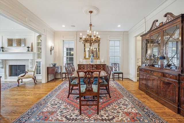 dining area featuring an inviting chandelier, ornamental molding, light wood-style floors, and a healthy amount of sunlight