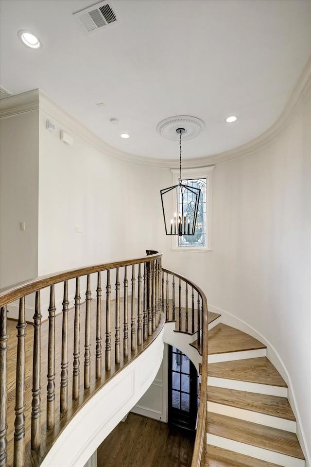 staircase featuring visible vents, crown molding, wood finished floors, and an inviting chandelier