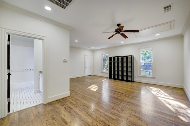 unfurnished living room featuring a ceiling fan, attic access, visible vents, crown molding, and baseboards
