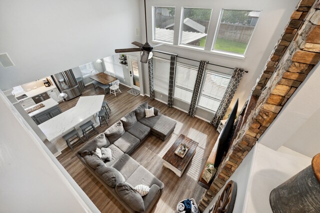 living area featuring a ceiling fan, wood finished floors, and a towering ceiling