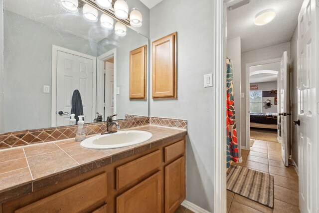 full bath featuring connected bathroom, tile patterned floors, visible vents, and vanity