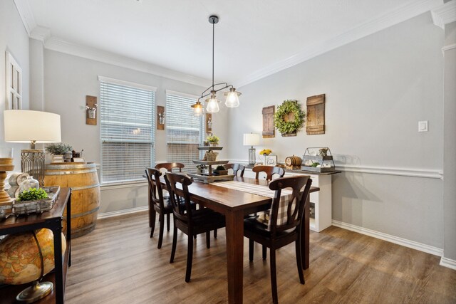 dining space featuring baseboards, ornamental molding, and wood finished floors