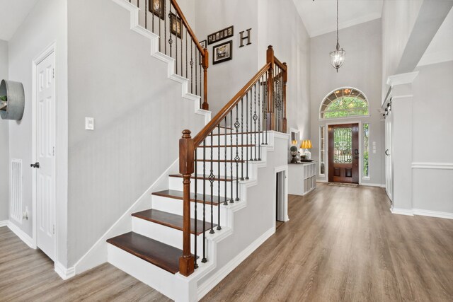 foyer with crown molding, baseboards, wood finished floors, a towering ceiling, and stairway