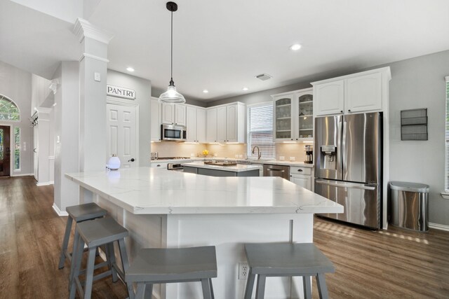 kitchen featuring a kitchen island, baseboards, appliances with stainless steel finishes, and a sink