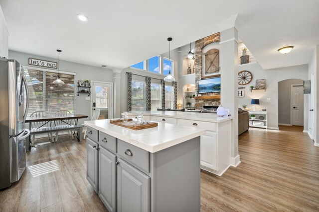kitchen with gray cabinets, light wood-type flooring, a kitchen island, and stainless steel refrigerator with ice dispenser
