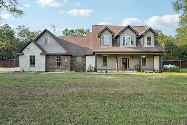 view of front of home with a porch, fence, a shingled roof, and a front yard