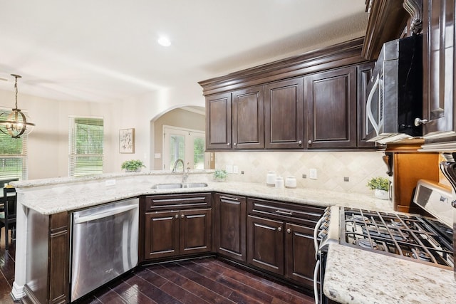 kitchen with dark brown cabinetry, dark wood-style flooring, appliances with stainless steel finishes, arched walkways, and a sink