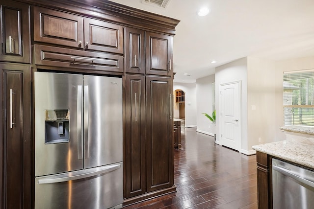 kitchen with arched walkways, dark wood finished floors, appliances with stainless steel finishes, and dark brown cabinetry