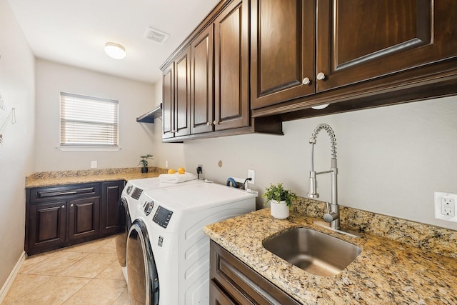 laundry area featuring visible vents, cabinet space, a sink, light tile patterned floors, and washer and clothes dryer