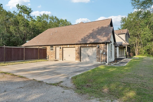 view of home's exterior with driveway, a garage, brick siding, fence, and a yard