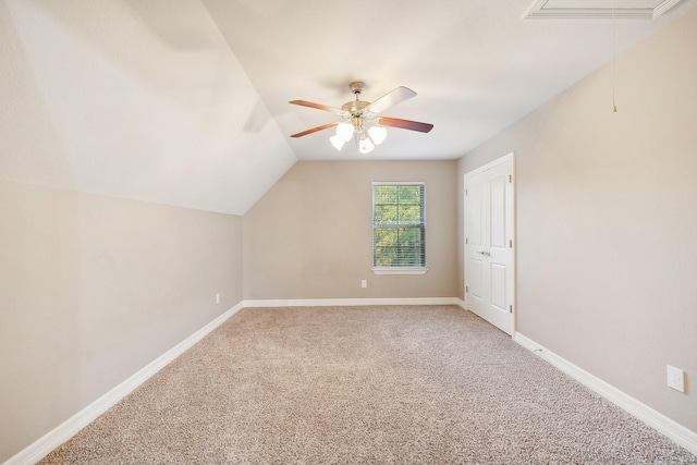 additional living space with light colored carpet, attic access, baseboards, and ceiling fan