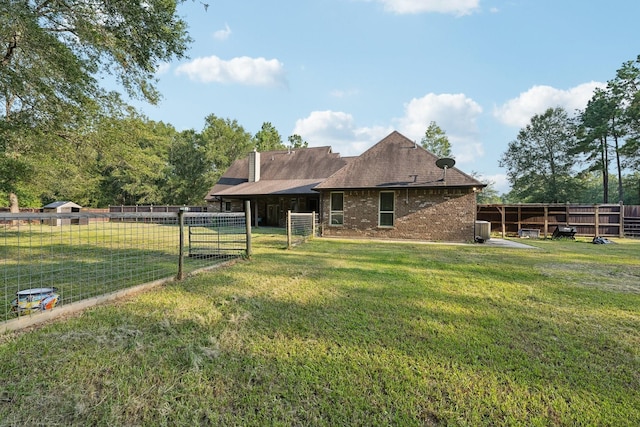 back of property featuring a lawn, fence, cooling unit, and brick siding