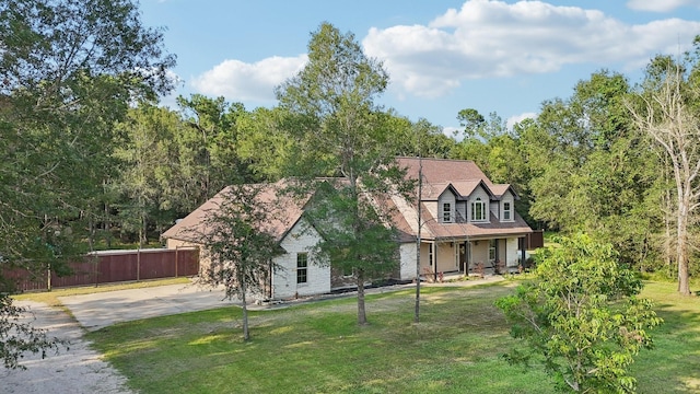 view of front facade featuring fence, stone siding, driveway, and a front yard