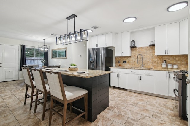 21894 Pinewilde Ct, Porter, TX 77365 - kitchen with a kitchen breakfast bar, visible vents, a center island, a sink, and stainless steel appliances