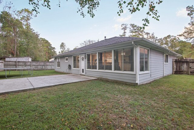 21894 Pinewilde Ct, Porter, TX 77365 - back of property with a lawn, a fenced backyard, a trampoline, and a patio area