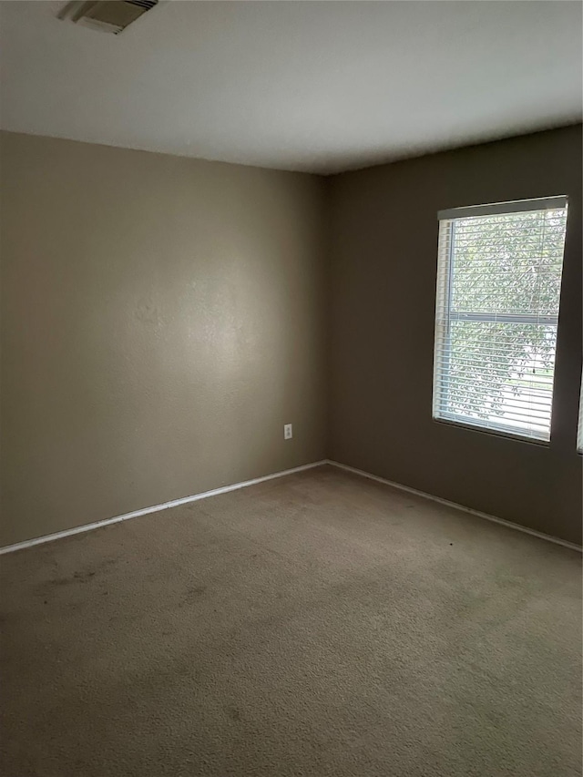 carpeted spare room with baseboards and visible vents
