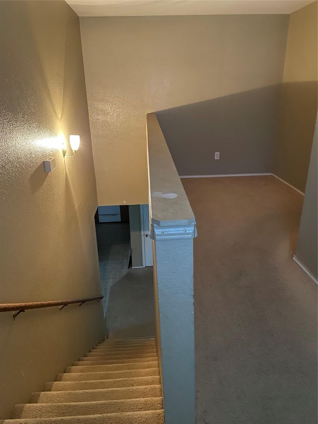 stairway with carpet floors, baseboards, and a textured wall