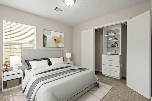 bedroom with light carpet, a textured ceiling, and visible vents