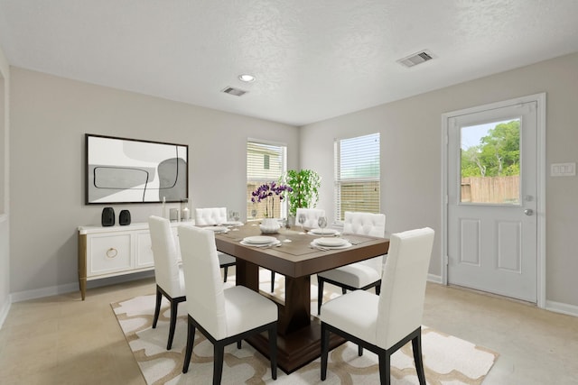 dining room with baseboards, a textured ceiling, and visible vents