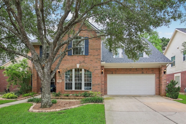 traditional-style house with a shingled roof, concrete driveway, and brick siding