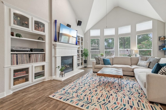 living area featuring high vaulted ceiling, wood finished floors, and a tile fireplace
