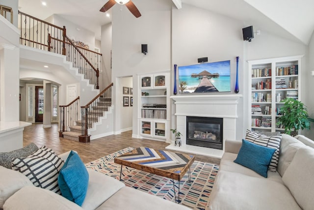 living area with high vaulted ceiling, ceiling fan, arched walkways, and stairs