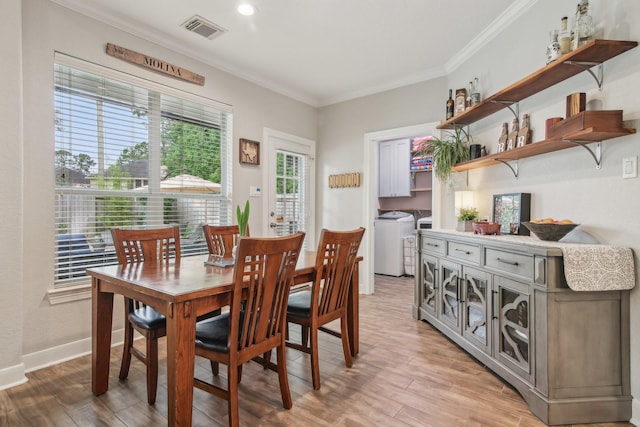 dining space featuring crown molding, light wood-style floors, baseboards, visible vents, and washer and clothes dryer