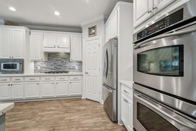 kitchen featuring ornamental molding, appliances with stainless steel finishes, white cabinets, and tasteful backsplash