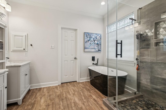 bathroom featuring crown molding, vanity, wood finished floors, baseboards, and a stall shower