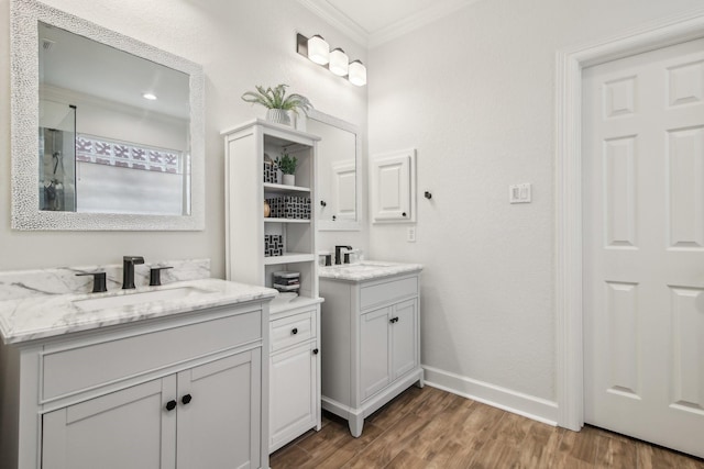 full bathroom featuring crown molding, a sink, baseboards, two vanities, and wood finished floors
