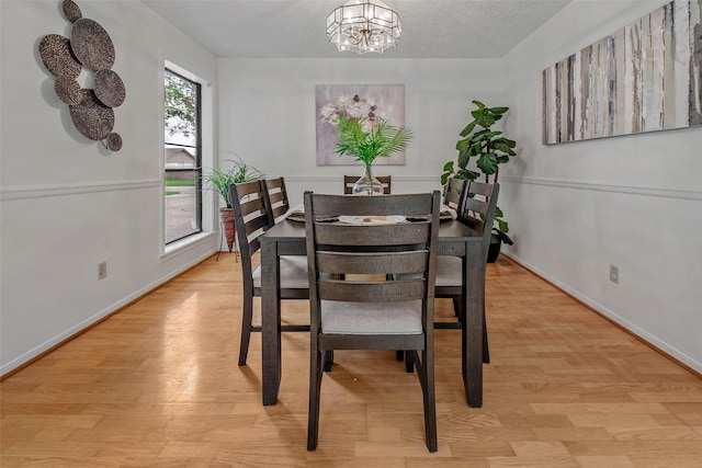 dining space featuring light wood-style floors, baseboards, and a notable chandelier