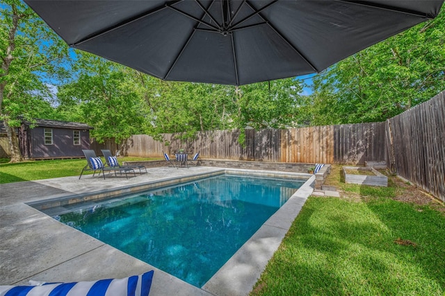 view of swimming pool with a fenced backyard, an outbuilding, a lawn, and a patio