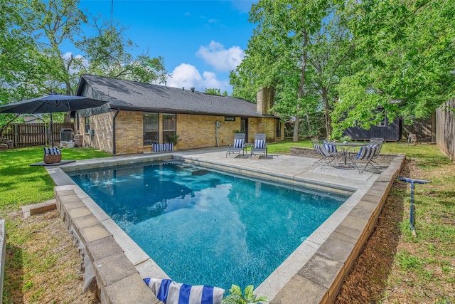 outdoor pool with a lawn, a fenced backyard, and a patio area