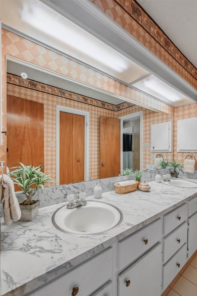 full bathroom featuring double vanity, wallpapered walls, a sink, and tile patterned floors