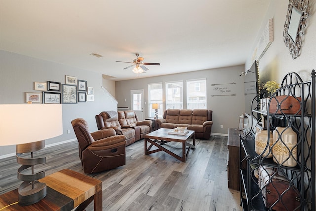 living room featuring a ceiling fan, baseboards, visible vents, and wood finished floors