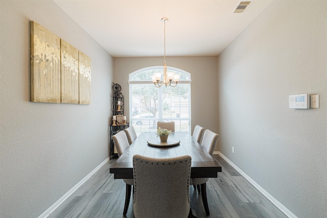 dining area featuring an inviting chandelier, baseboards, wood finished floors, and visible vents