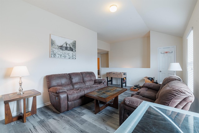 living room featuring baseboards, vaulted ceiling, and wood finished floors